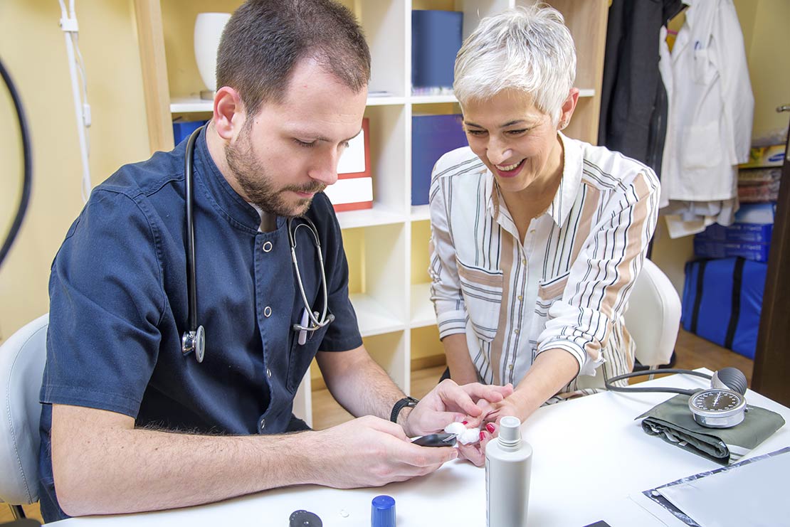 Healthcare worker preparing an elderly woman for an insulin resistance test.