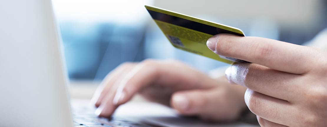 Woman with credit card at computer. Payment options are available for medical laboratory services provided in Boise, Garden City, Meridian, Nampa, Idaho Falls, Pocatello and Rexburg