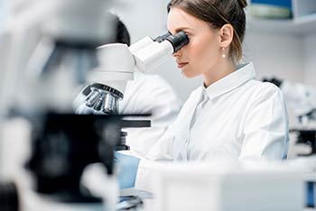 Female medical lab worker looking through a microscope. We support doctor's offices in Boise, Garden City, Meridian, Idaho Falls, Pocatello and Rexburg.