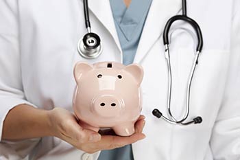 Doctor holding a piggy bank representing saving money on our Employee Wellness Program located in our Boise, Garden City, Meridian, Idaho Falls, Pocatello and Rexburg areas.