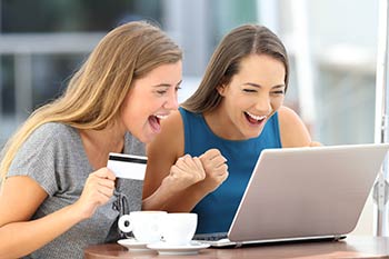 Two happy young adult women making payments online for wellness services including custom test panels in Boise, Garden City, Meridian, Idaho Falls, Pocatello and Rexburg.